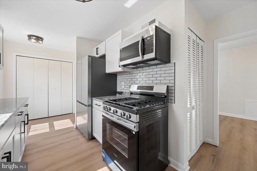 Kitchen with a stainless-steel gas range, white subway-tile backsplash, and light wood flooring.