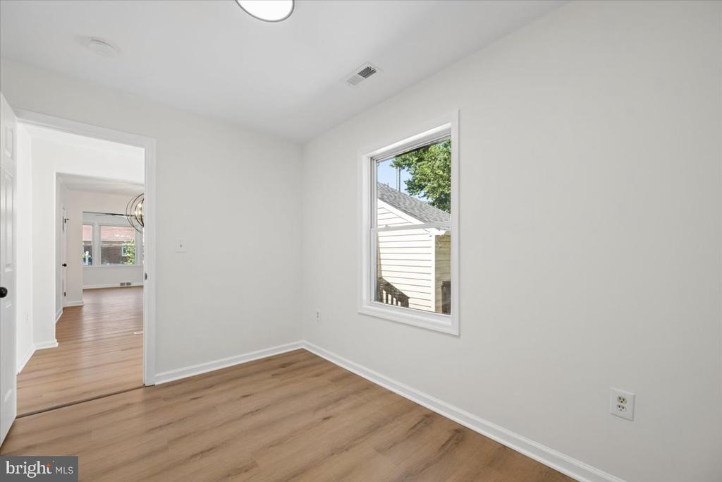 Empty room with wood-look flooring, white walls, and a single window.
