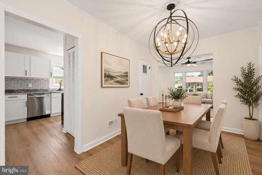 Staged dining room with a wooden table, orb chandelier, and views into the kitchen and living room.