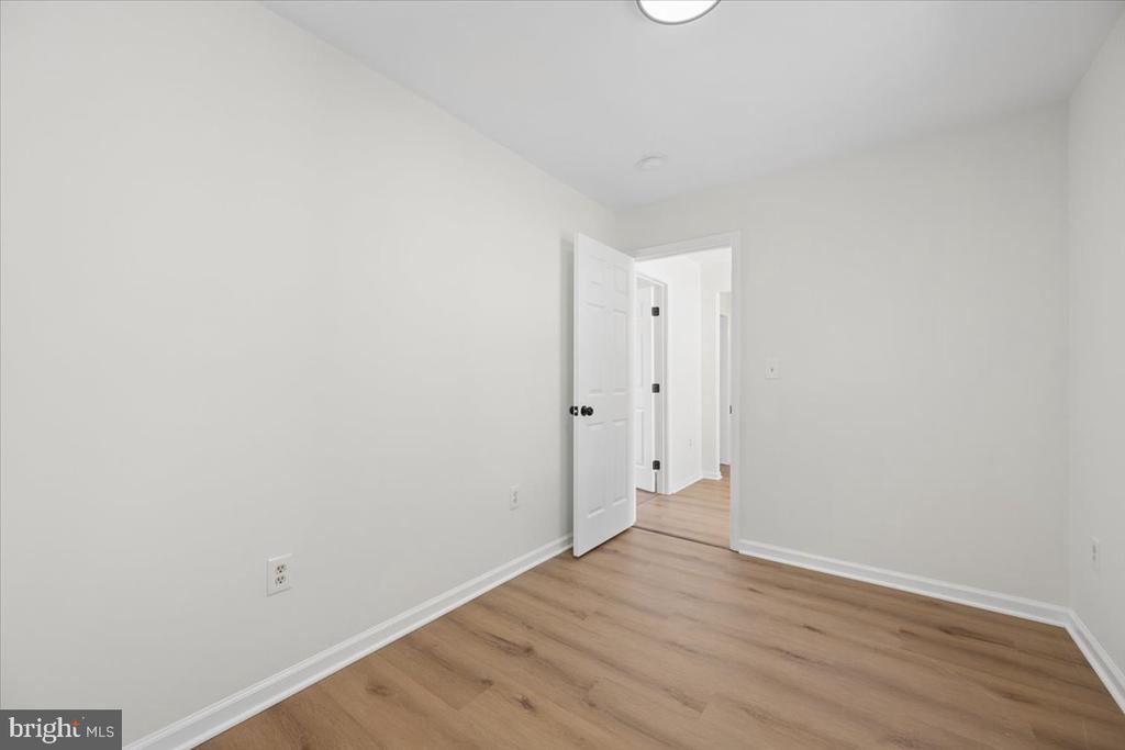 Empty room with light wood-look floors and an open doorway to the hall.