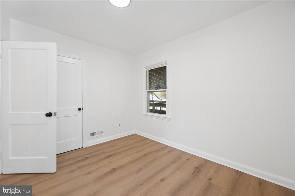 Empty room with light wood flooring, white walls, and a window.