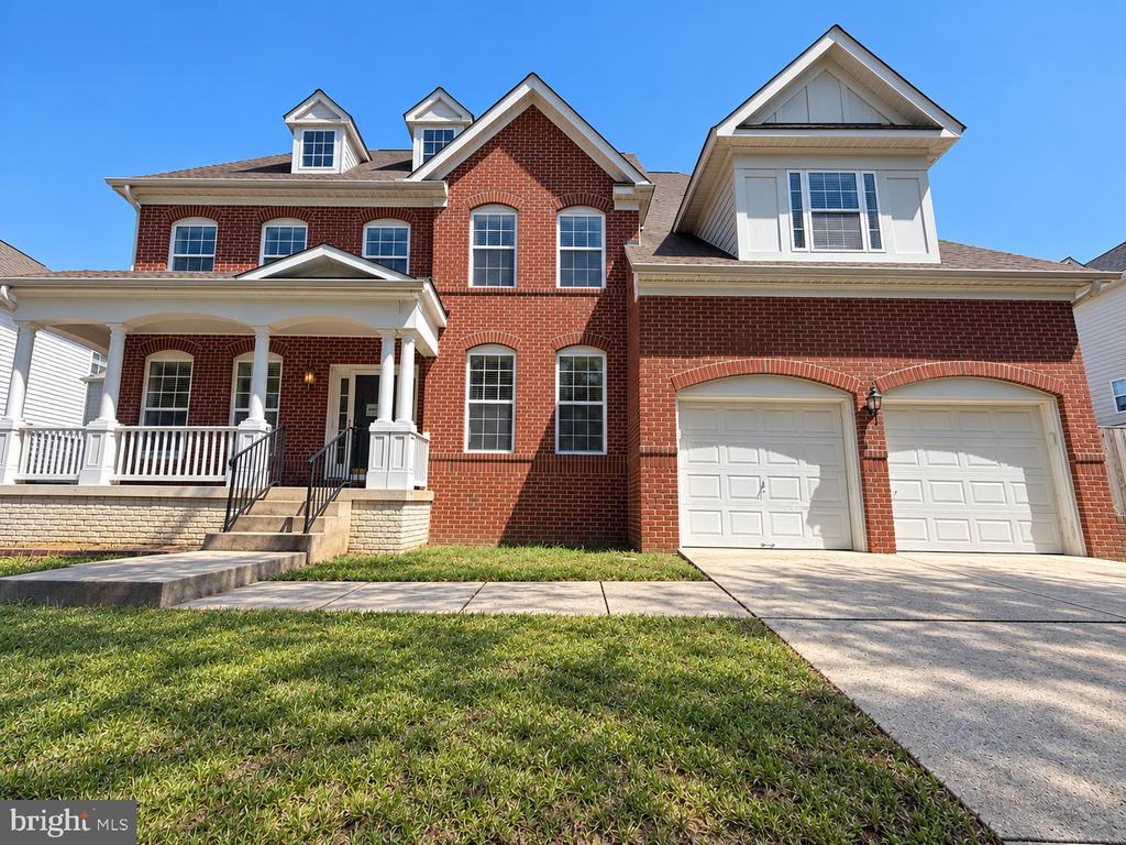 Red brick house with a covered porch, two dormers, and a two-car garage.