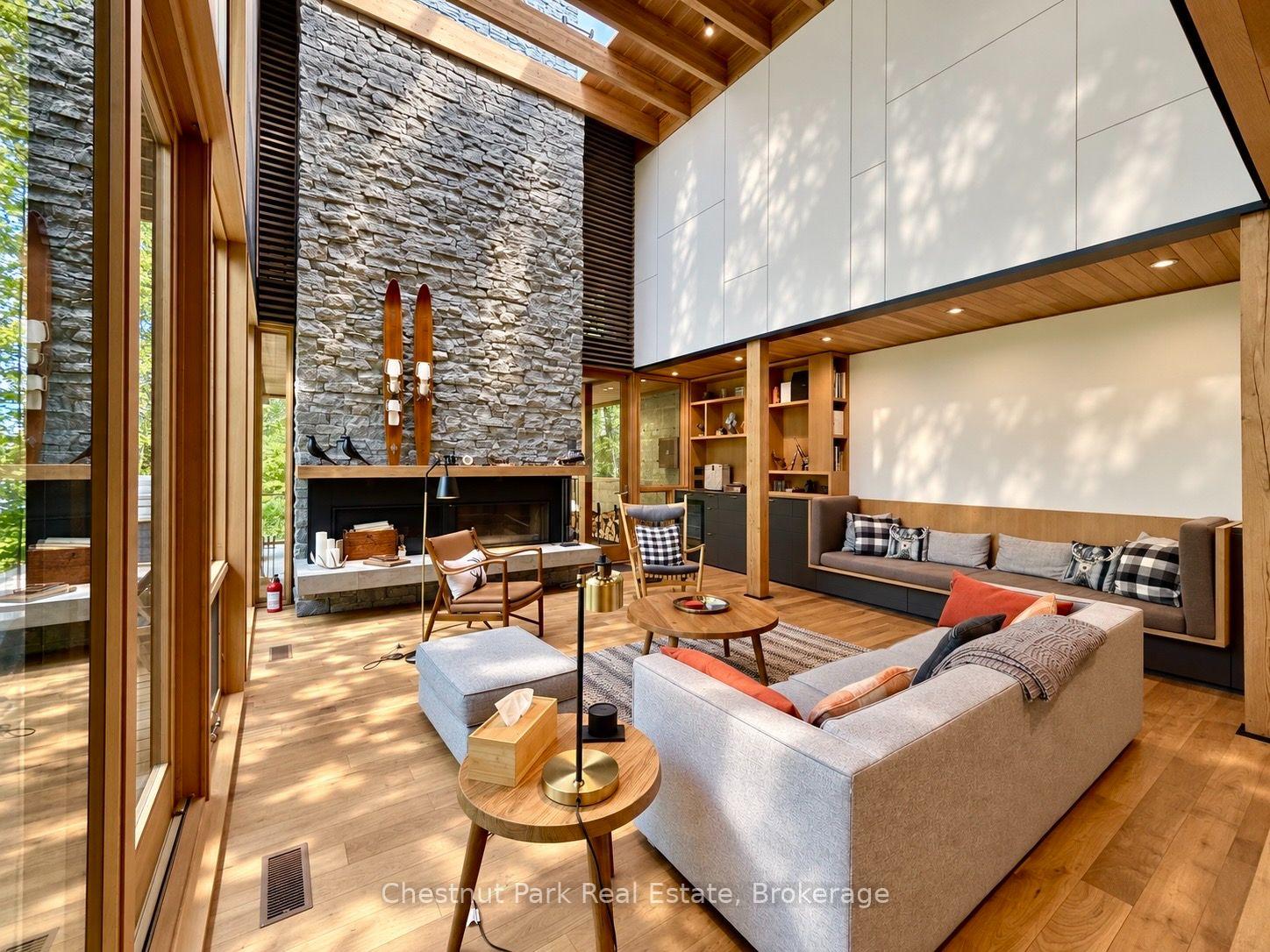 Living room with a vaulted wood ceiling, stone fireplace, and floor-to-ceiling windows.