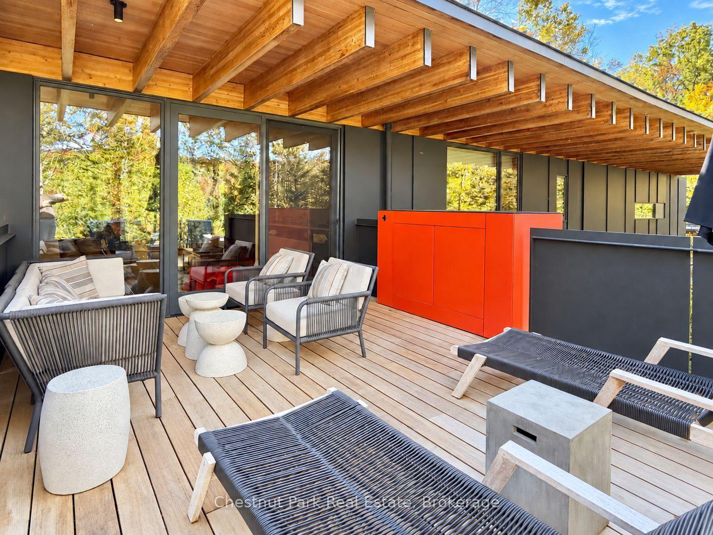 Outdoor deck with timber roof, lounge seating, and a bright red outdoor kitchen cabinet.