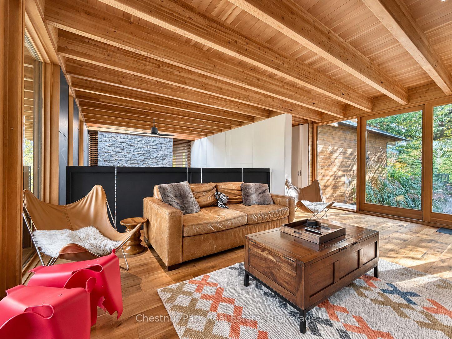 Living room with a vaulted wood ceiling, tan leather sofa, and large windows.