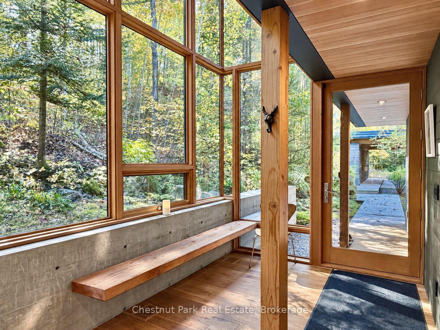 Wood-and-glass entry sunroom with a long built-in bench and woodland views.