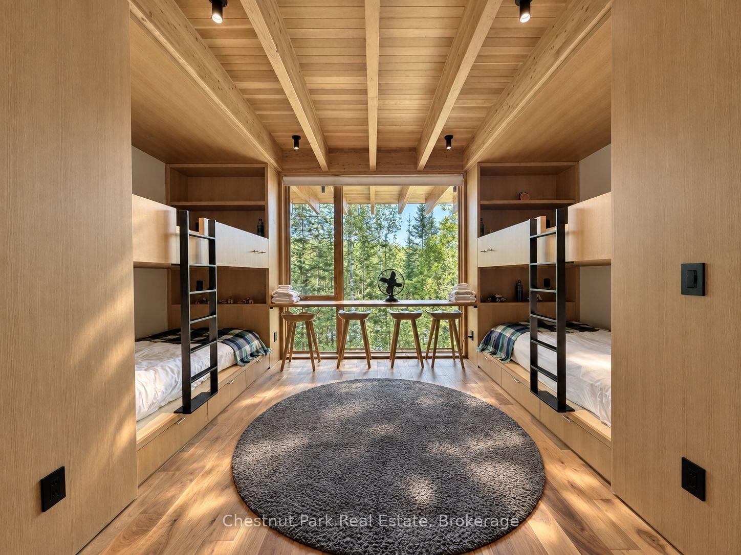 Bedroom with built-in twin beds, a vaulted wood ceiling, and a large window overlooking trees.