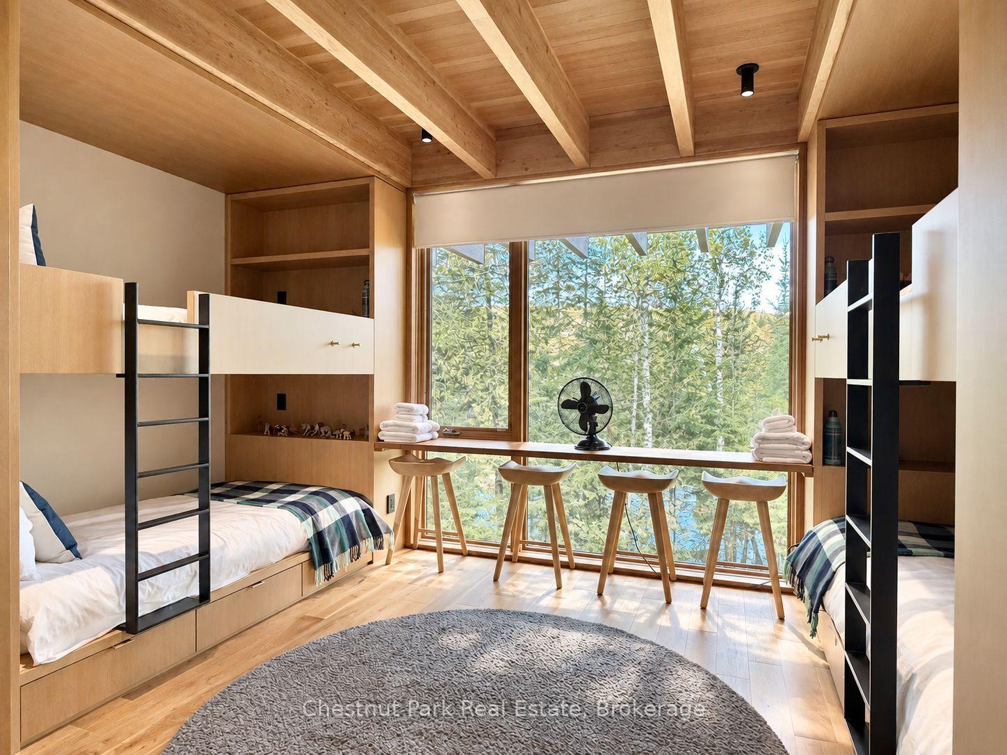 Bedroom with twin built-in beds, timber ceiling, and a wide window overlooking trees and water.