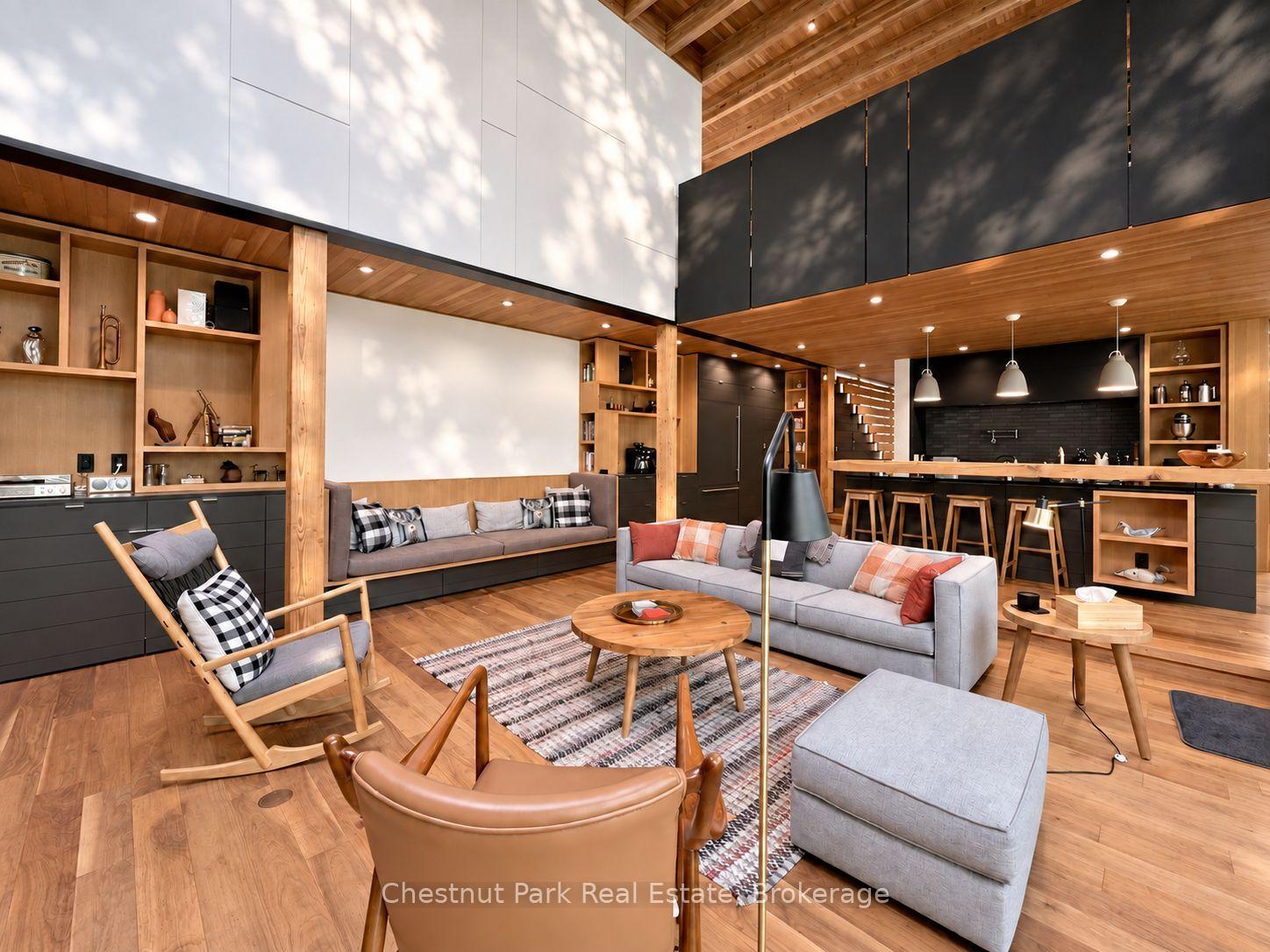 Open-plan living room and kitchen with vaulted wood ceiling, built-in shelving, and island seating.