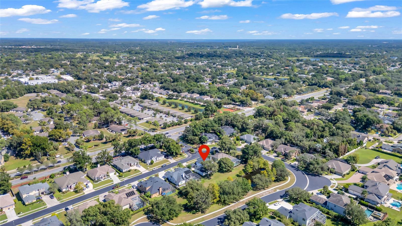 Aerial view of a tree-lined Casselberry neighborhood, with a red pin marking the property.