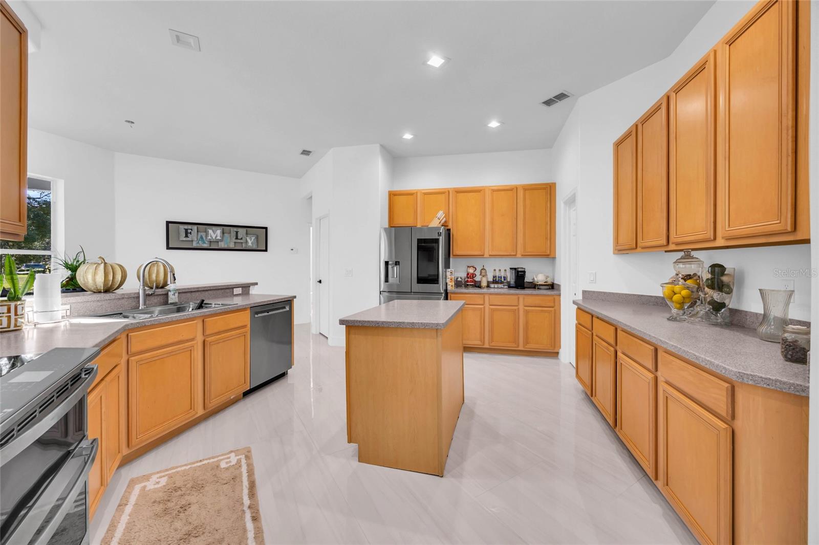 Kitchen with honey-colored cabinets, a central island, gray countertops, and stainless steel appliances.