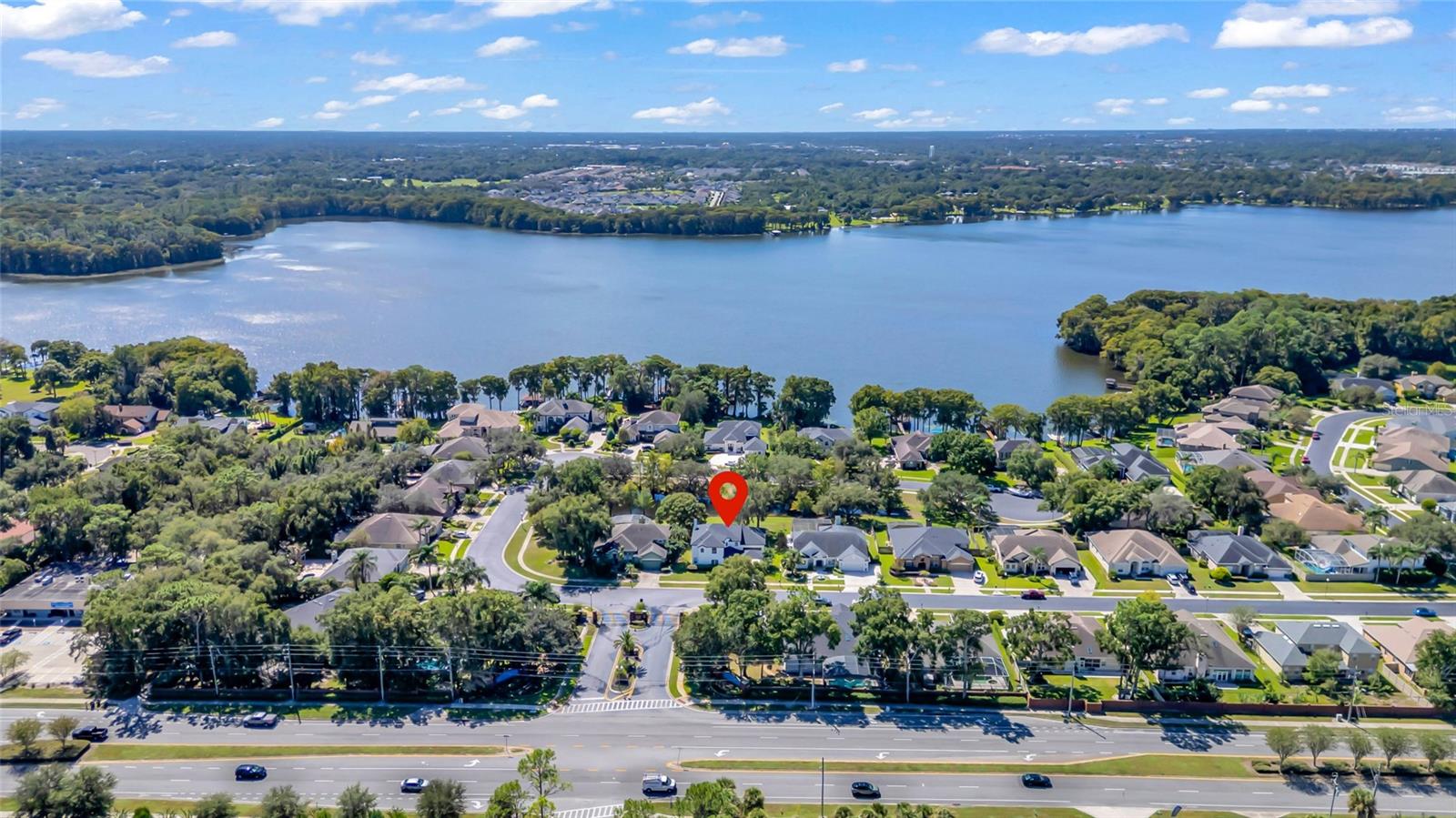 Aerial view of a lakefront neighborhood, with a red pin marking a home near the water.