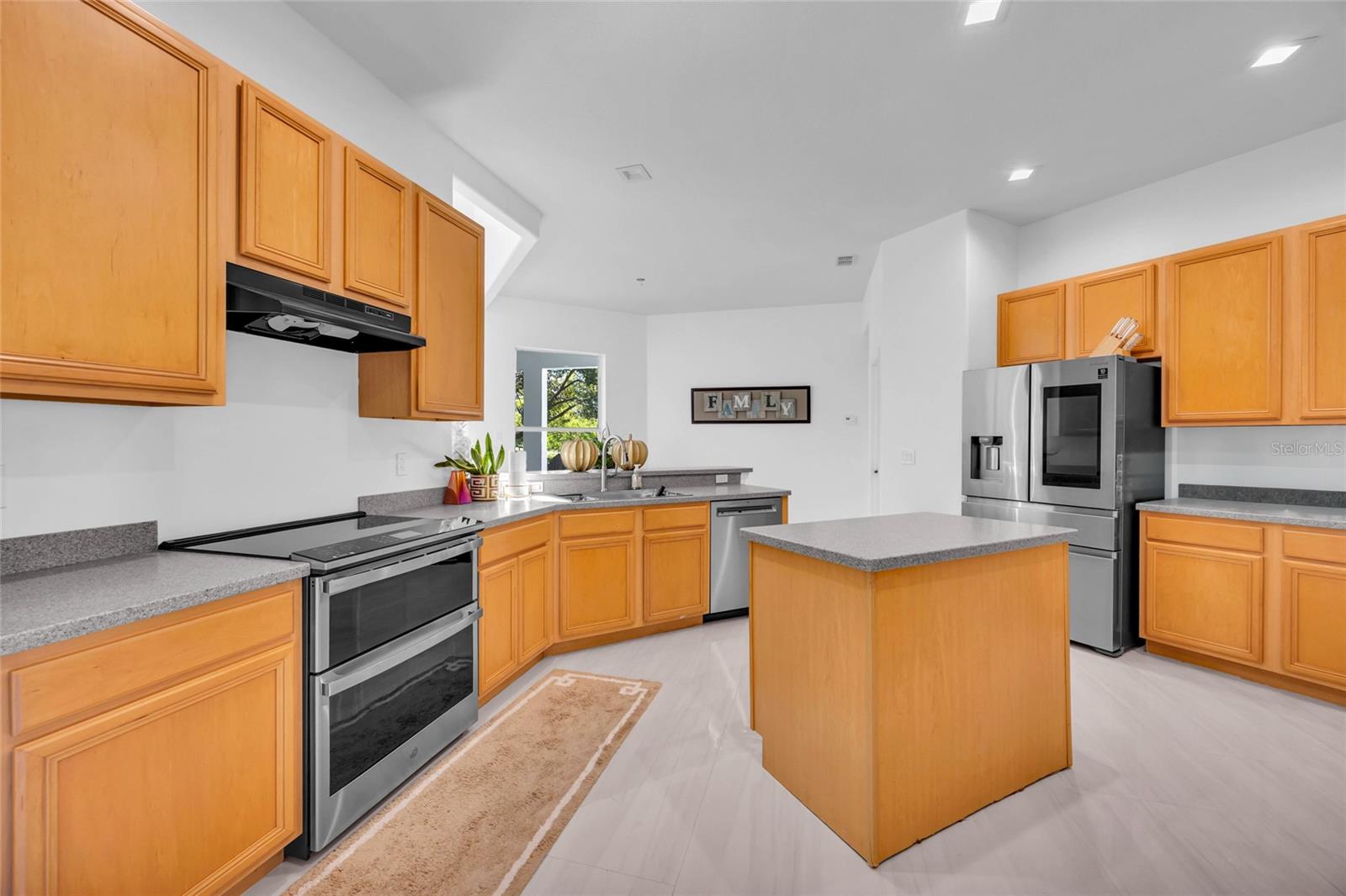 Kitchen with warm wood cabinetry, a central island, and stainless steel appliances.