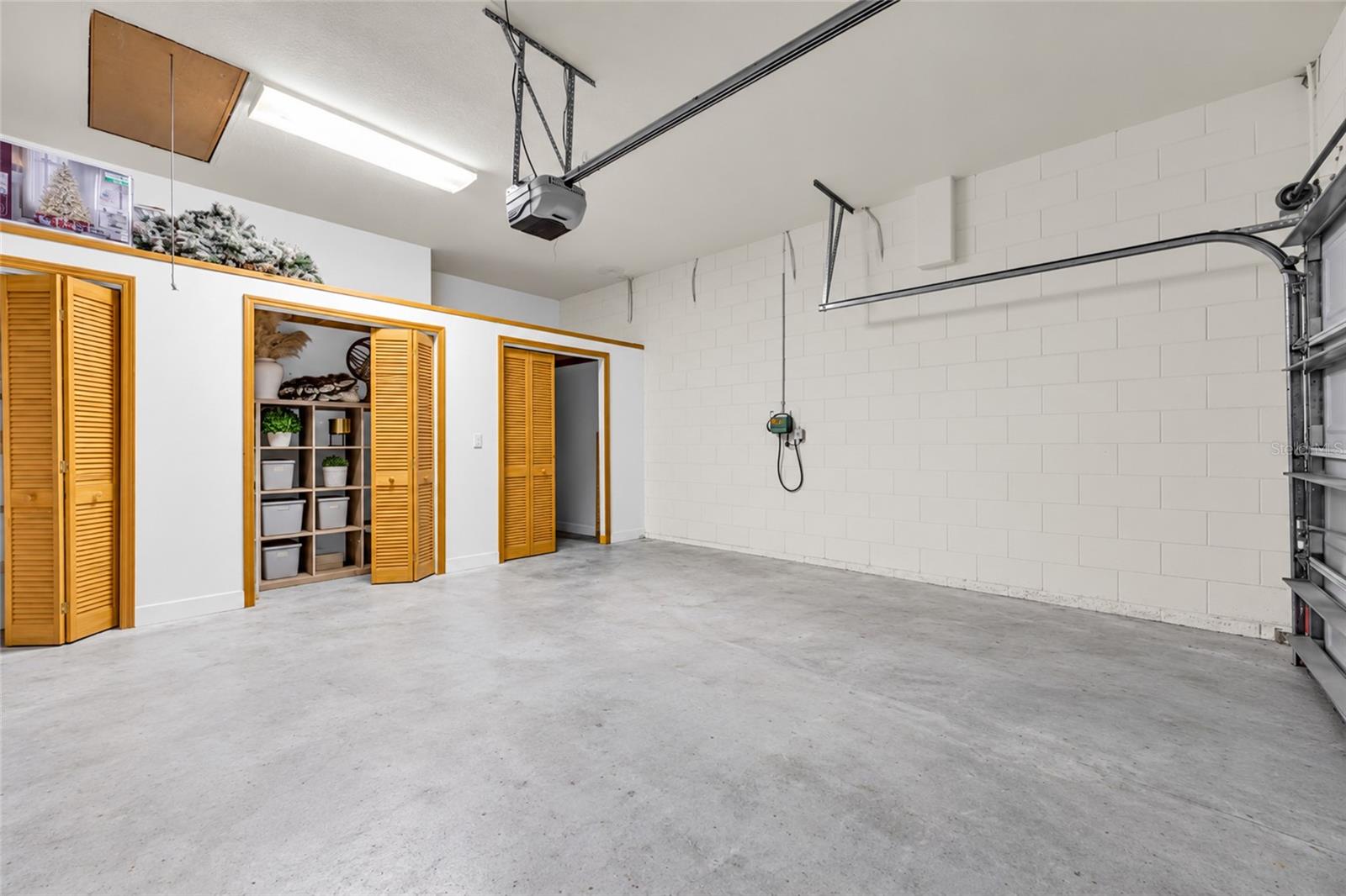 Empty garage with a concrete floor and wooden louvered storage cabinets.