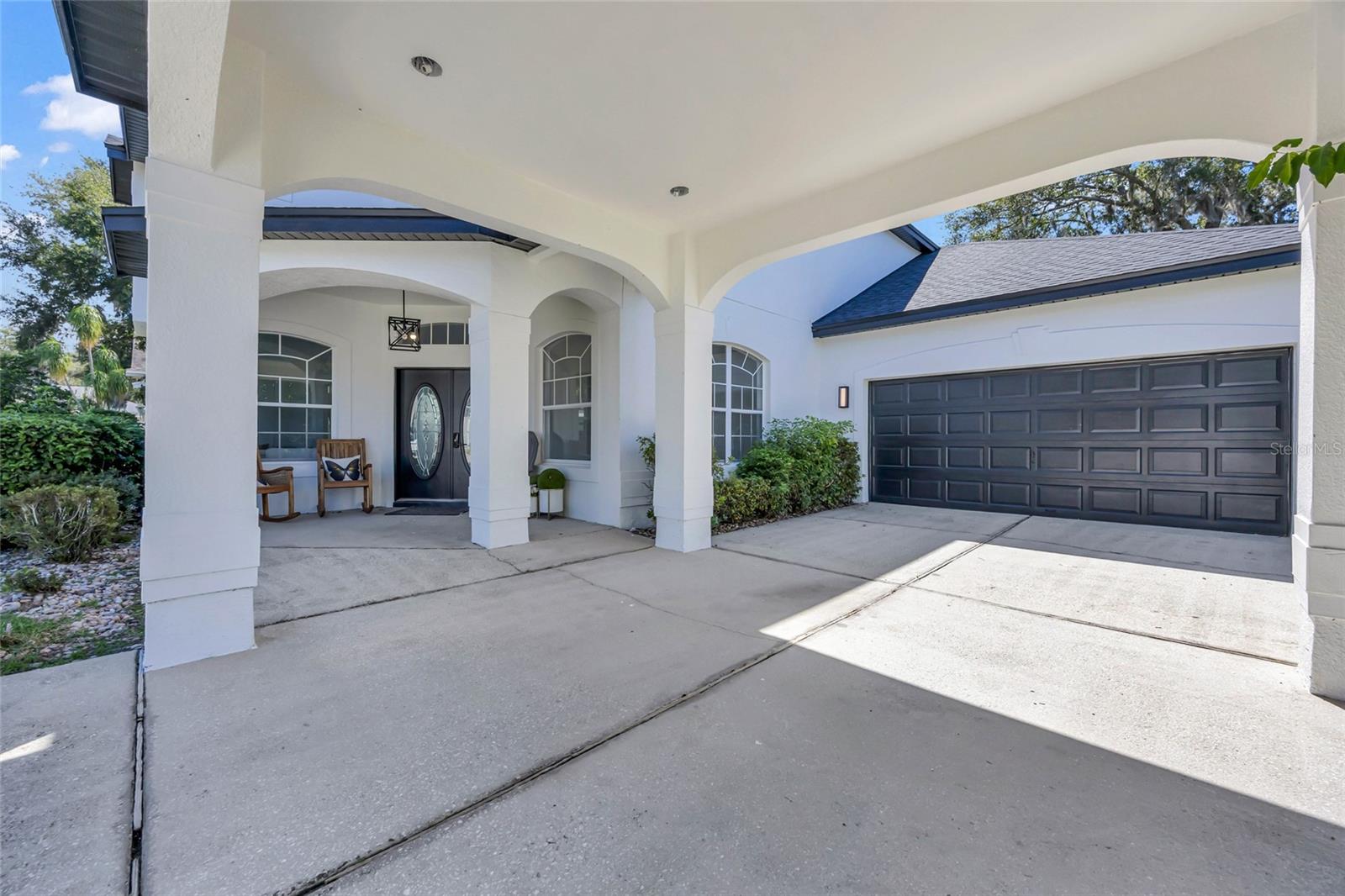 Home exterior with an arched covered entry, dark double front doors, and a large double garage door.