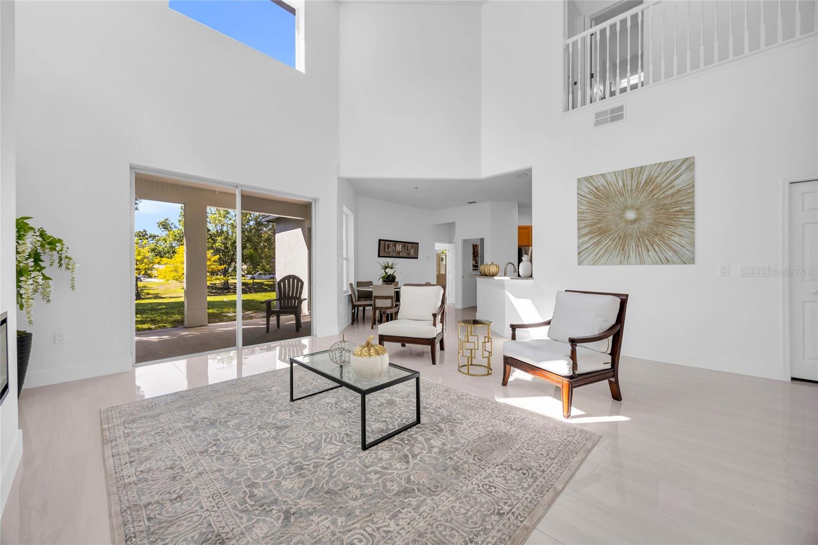 Bright living room with vaulted ceilings, sliding patio doors, and a view of the grassy yard.
