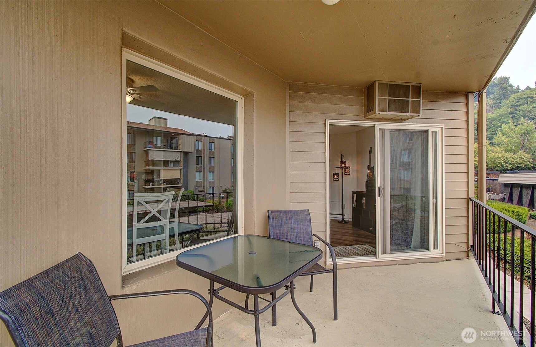 Covered balcony with glass-top table and chairs beside a sliding glass door.