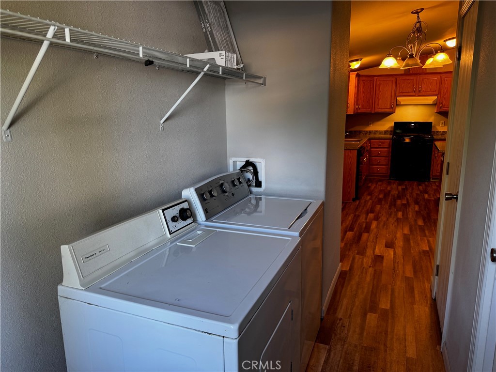 Laundry room with washer and dryer, storage shelf, and doorway to the kitchen.