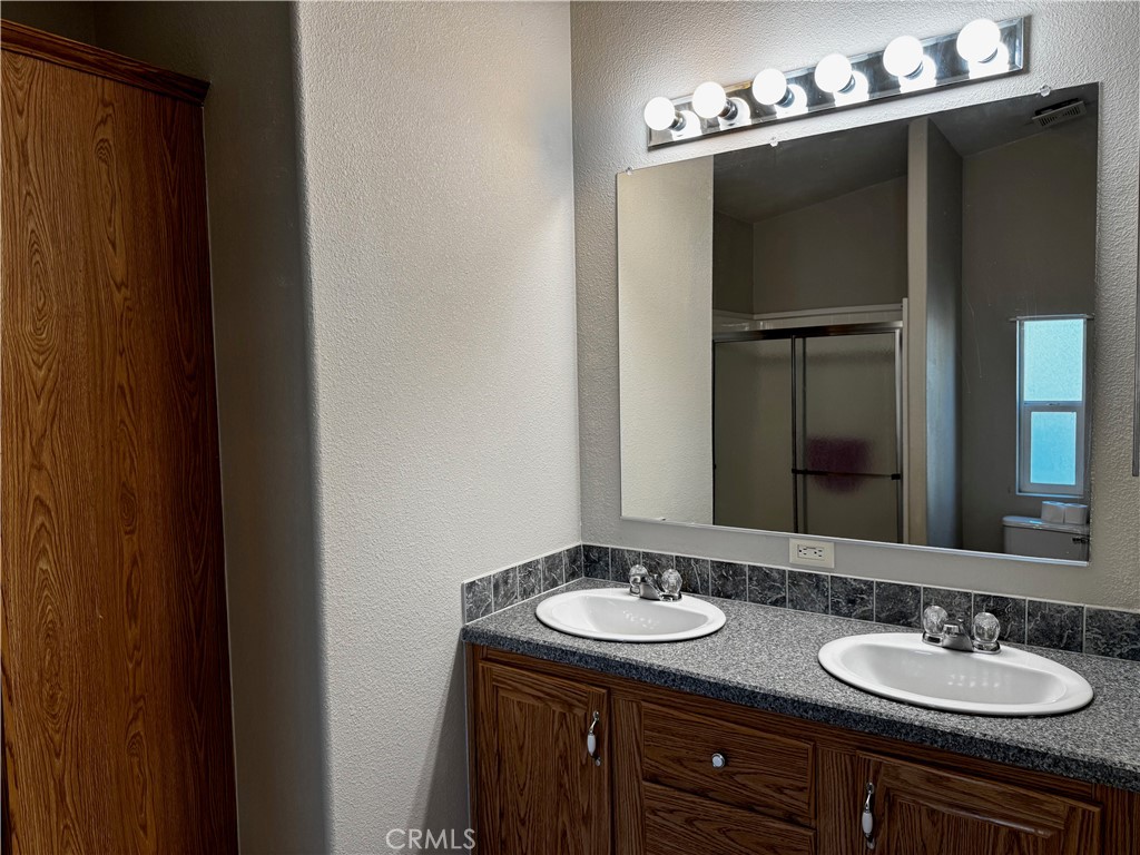 Bathroom double vanity with a gray countertop, dark wood cabinets, and a large mirror.