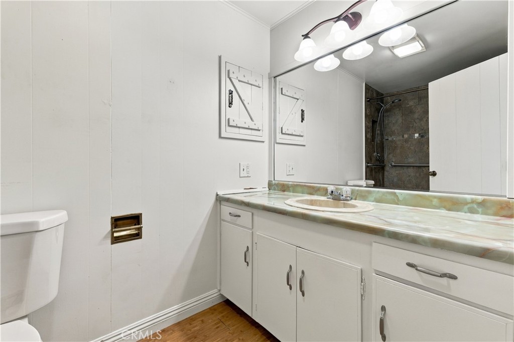 Bathroom with a long white vanity, marbled countertop, large mirror, and dark tiled shower.