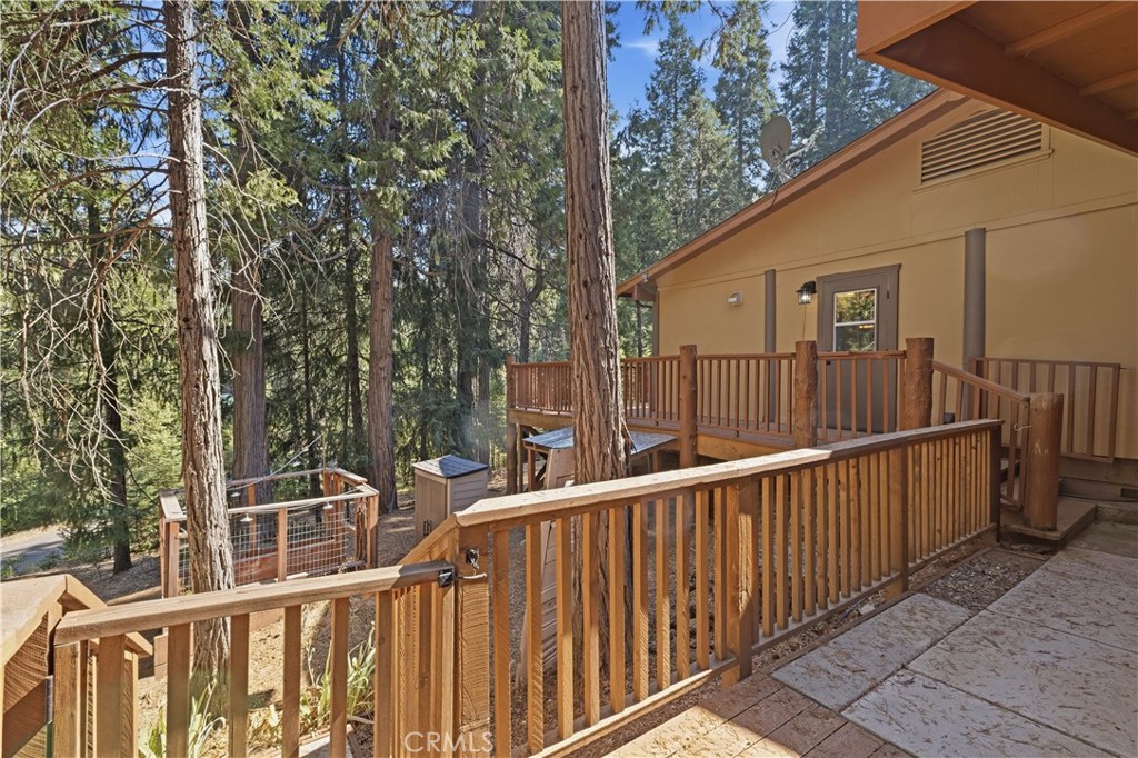 Home’s raised wooden deck and railings surrounded by tall pine trees.