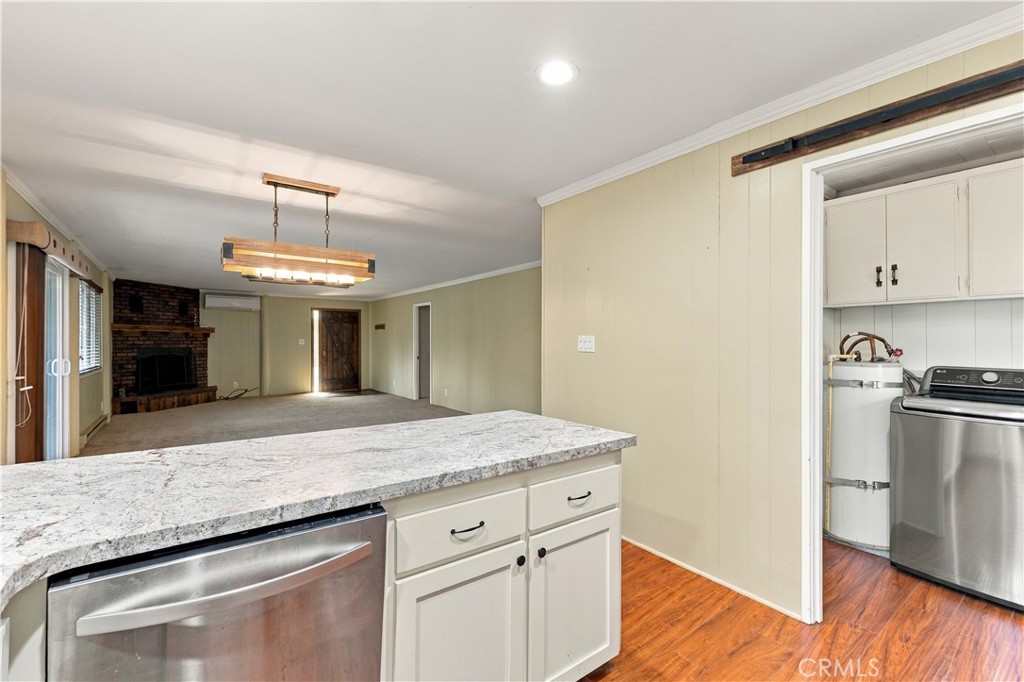 Kitchen island with granite countertop opens to an unfurnished living room and laundry area.
