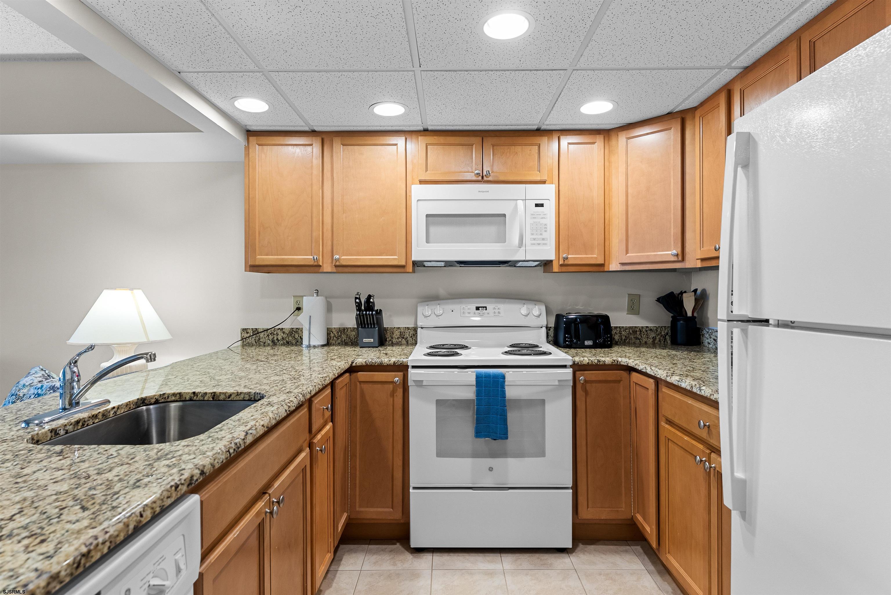 Kitchen with honey-colored cabinets, granite counters, and white appliances.