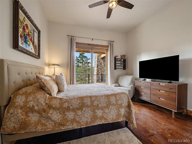 Furnished bedroom with a large bed, wood floors, and a glass door opening to a balcony.