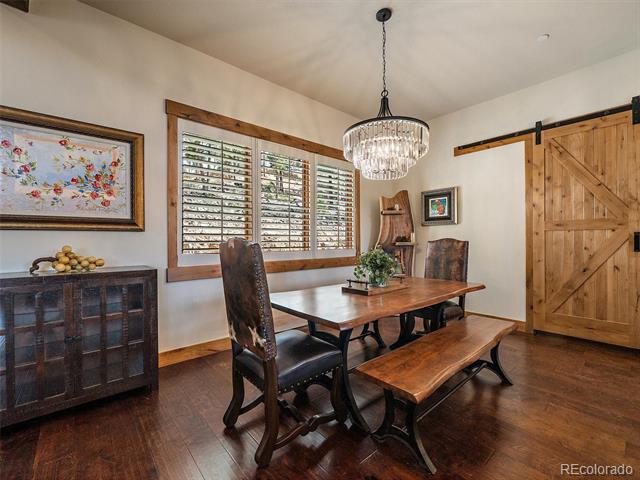 Dining room with a wood table and bench, shuttered windows, and a sliding barn door.