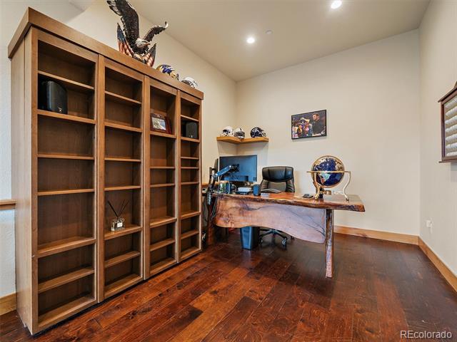 Home office with built-in wood bookcases, a desk, and dark hardwood floors.