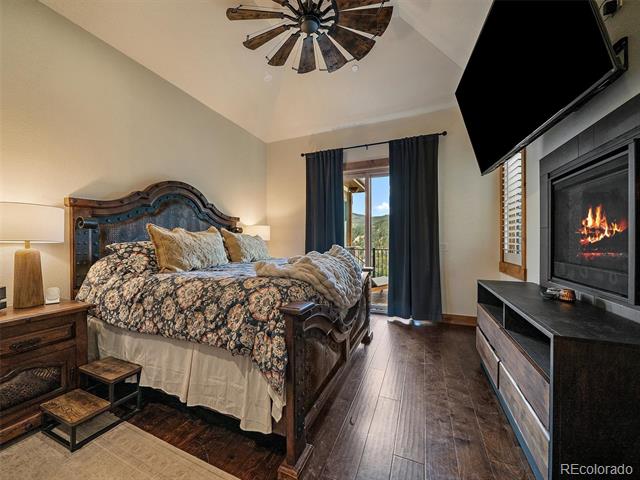 Bedroom with carved wooden bed, vaulted ceiling, fireplace, and balcony doors.