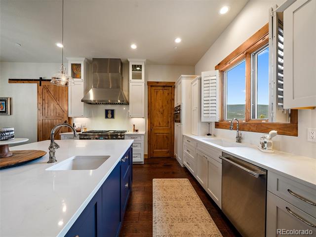 Kitchen with a navy-blue island, stainless steel appliances, and a large wood-trimmed window.