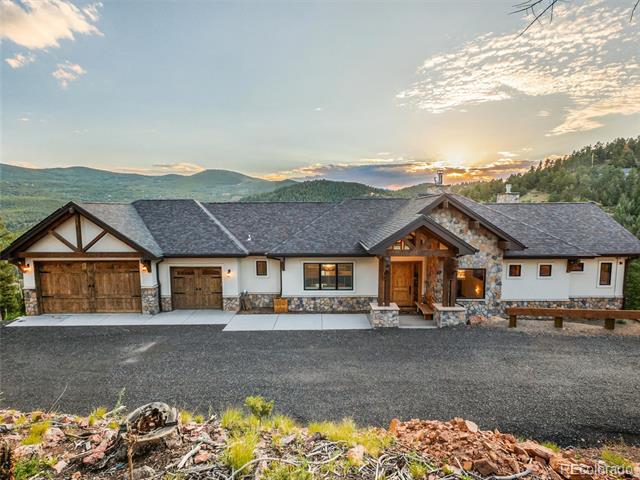 Single-story mountain home with two garages and stone accents at sunset.