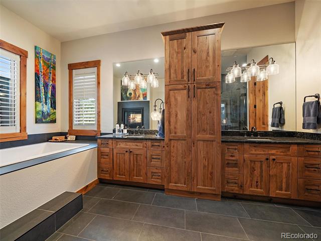 Bathroom with a built-in soaking tub and wood vanity with a central cabinet tower.