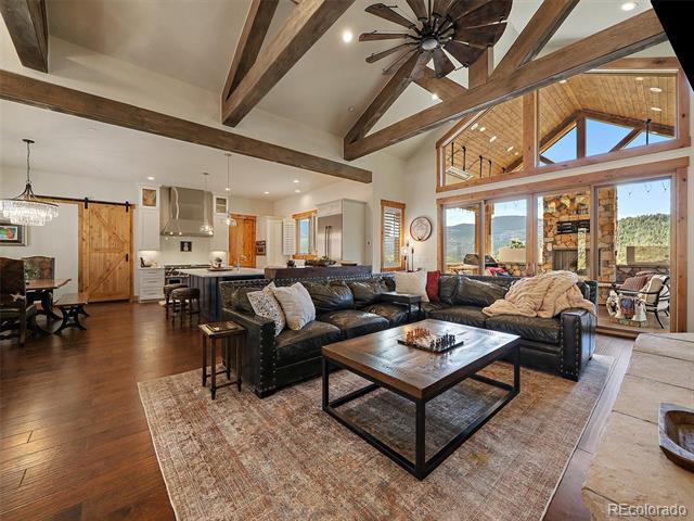 Living room with vaulted timber beams, a leather sectional, and mountain views through large windows.