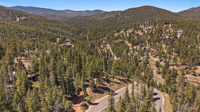 Aerial view of a wooded mountain neighborhood with scattered homes and a winding road.
