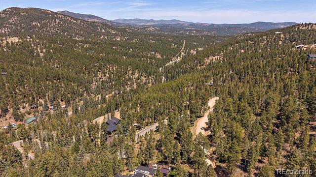 Aerial view of a wooded mountain property with scattered homes and distant ridgelines.