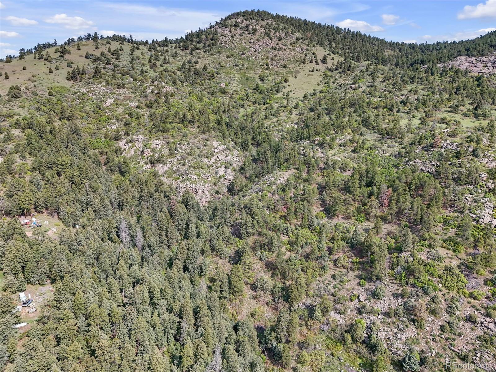 Aerial view of rocky, forested mountain land with a prominent ridge and scattered clearings.