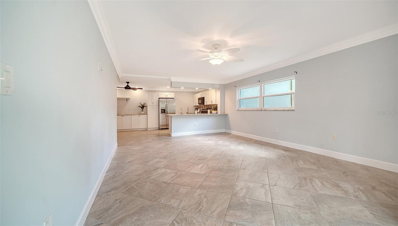 Open living area with large tile floors, a breakfast bar, and a white kitchen.