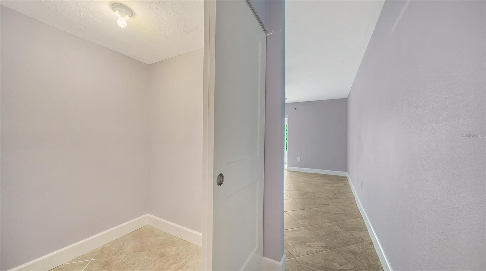 Tiled hallway beside an open white door and empty alcove.