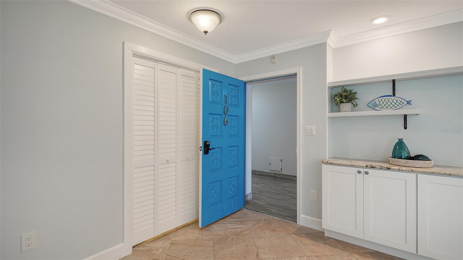 Entry foyer with a blue door marked 106, louvered closet doors, and built-in cabinetry.