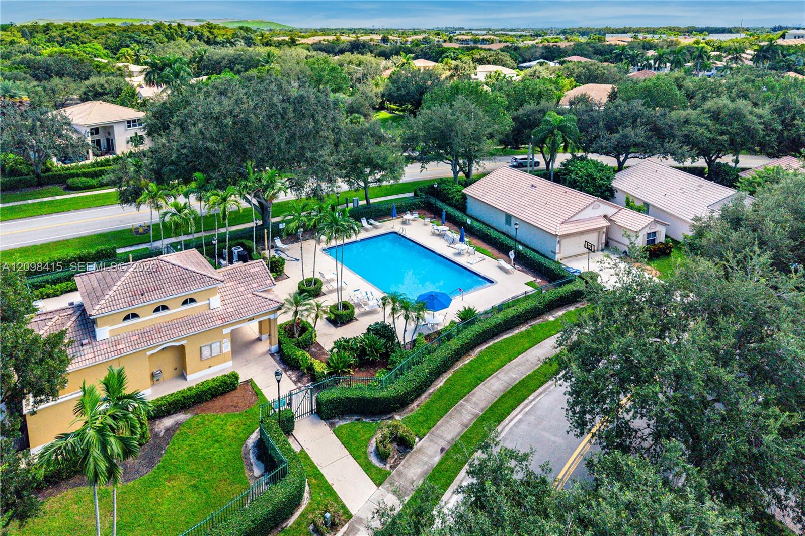Aerial view of a community pool surrounded by homes, palms, and landscaped grounds.