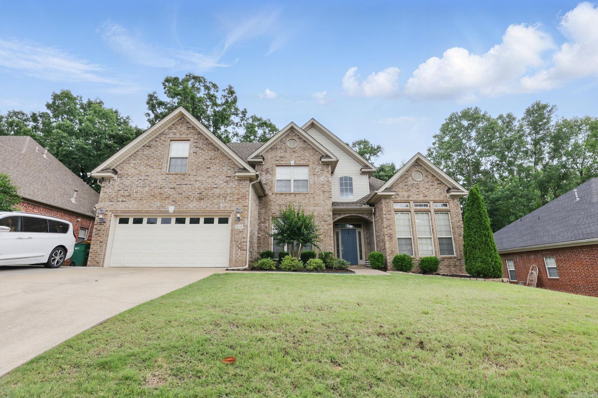 Two-story brick house with a double garage, blue front door, and broad front lawn.