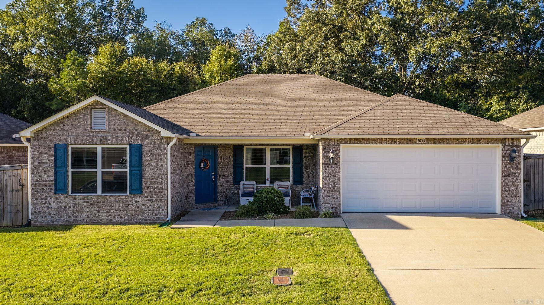 Brick house with blue shutters, a covered seating porch, and a two-car garage.