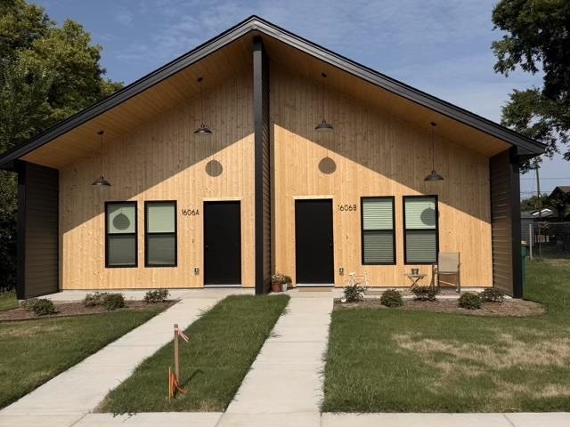 Wood-clad duplex with two entrances, a peaked roof, and separate concrete walkways.