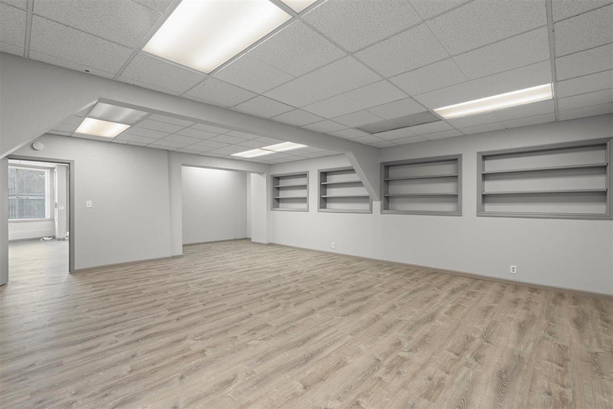 Vacant room with built-in shelves, wood-look flooring, and a suspended ceiling