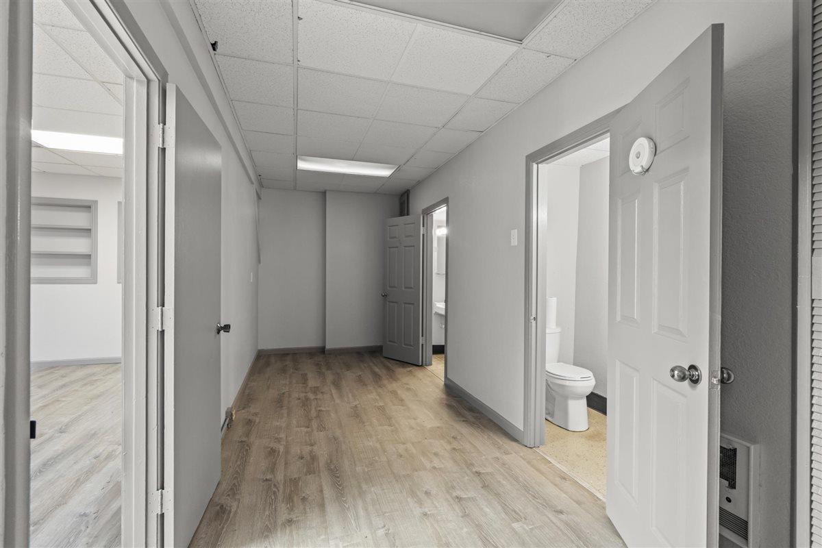 Hallway with wood-look flooring and open doorways, including a bathroom.