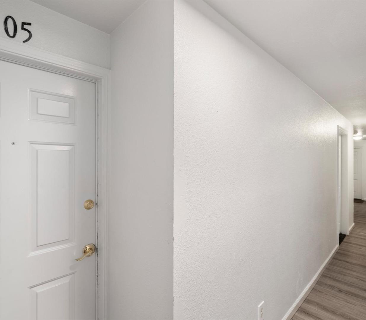 Interior hallway with a white paneled door marked 05 and gray wood-look flooring.