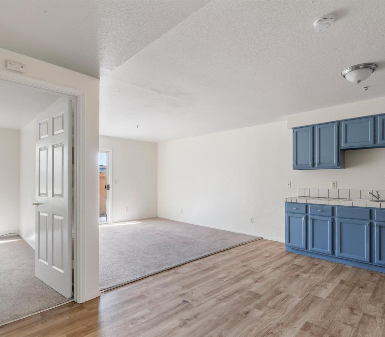 Open-plan kitchen and living area with blue cabinets and wood-look flooring.