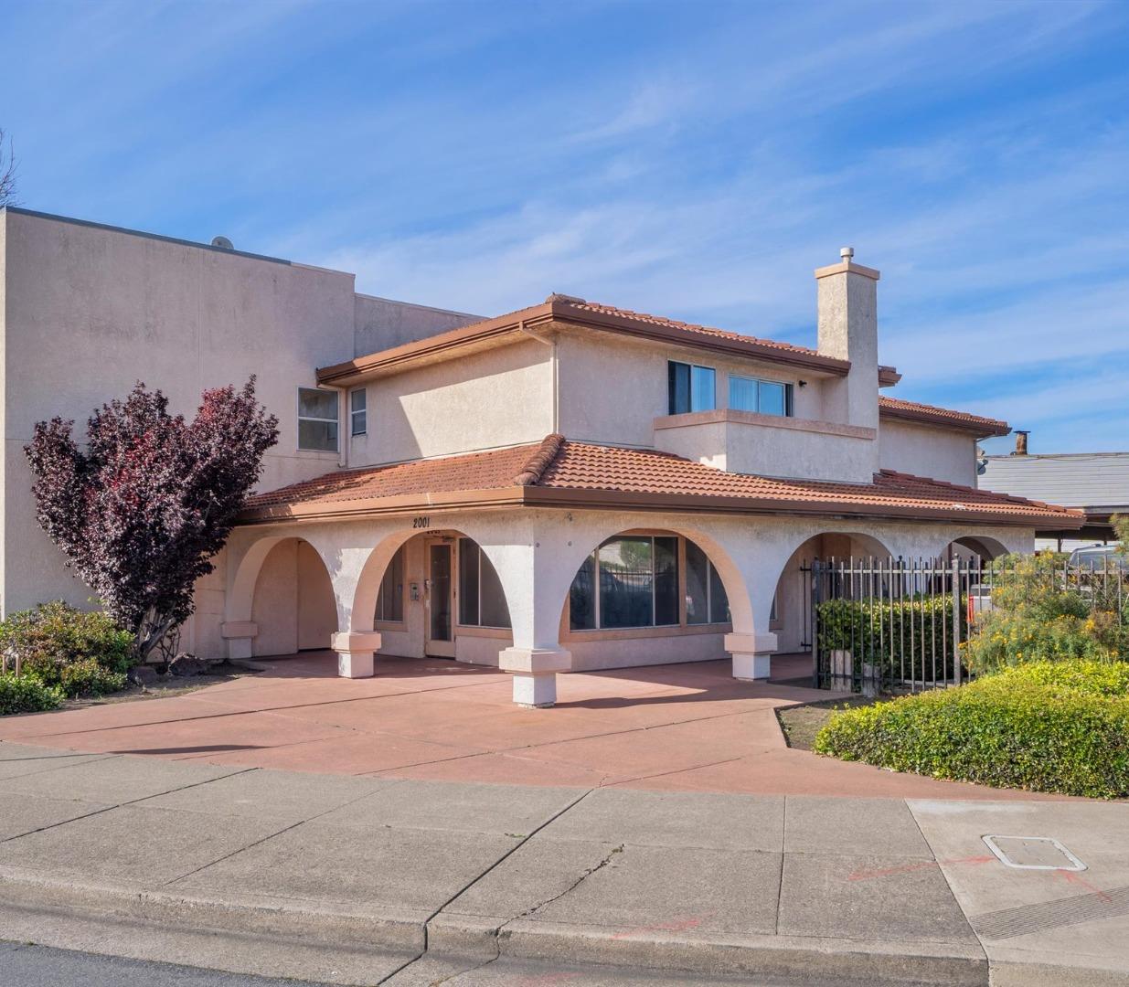 Two-story stucco building with a red tile roof and arched porch at 2001 Broadway Ave.